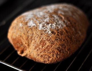 A loaf of Olandshvedebrod resting on a cooling rack, showcasing its golden crust and inviting texture