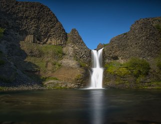 A stunning view of the Selfoss Waterfall cascading into a river, surrounded by natural beauty and rugged terrain