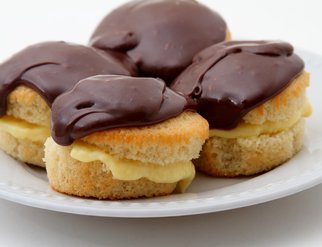 A plate featuring three Boston Cream Pies, each adorned with rich chocolate frosting